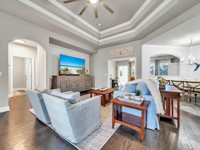 living room featuring ceiling fan with notable chandelier, a raised ceiling, ornamental molding, and dark hardwood / wood-style floors