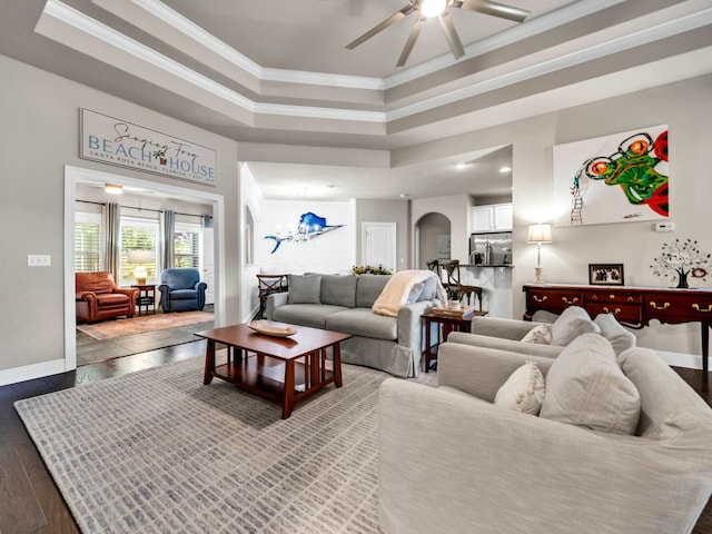 living room featuring ceiling fan with notable chandelier, hardwood / wood-style flooring, ornamental molding, and a tray ceiling