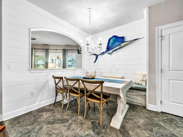 dining space with wooden walls, breakfast area, and a chandelier