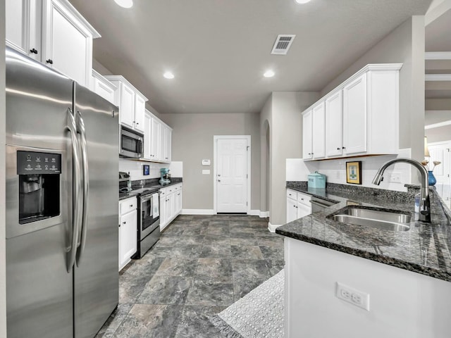 kitchen featuring sink, stainless steel appliances, white cabinetry, and dark stone countertops