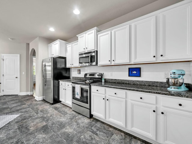 kitchen with decorative backsplash, white cabinetry, dark stone counters, and appliances with stainless steel finishes