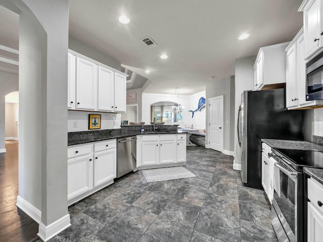 kitchen with kitchen peninsula, decorative light fixtures, white cabinets, appliances with stainless steel finishes, and sink