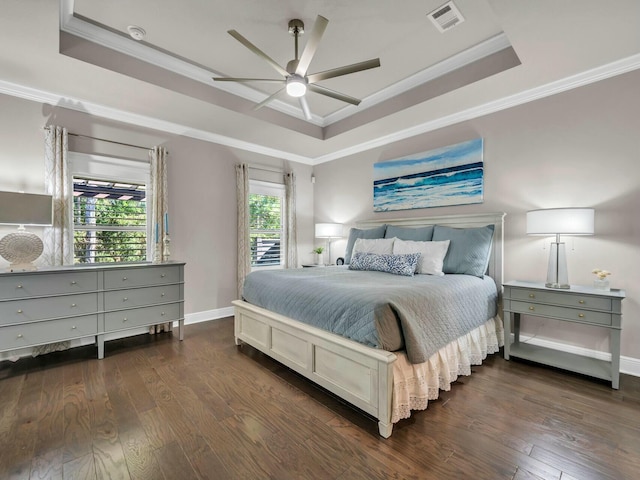 bedroom featuring ceiling fan, crown molding, dark hardwood / wood-style floors, and a tray ceiling