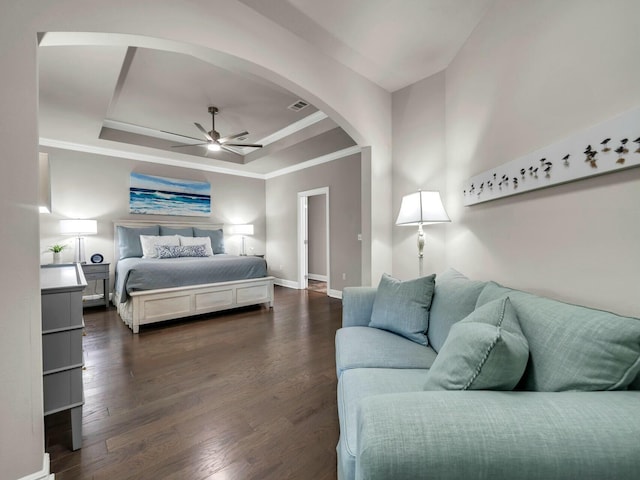 bedroom featuring ceiling fan, crown molding, dark hardwood / wood-style floors, and a tray ceiling