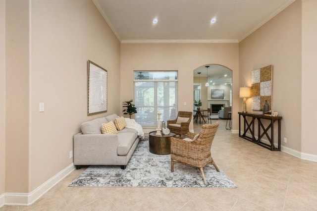 sitting room with baseboards, ornamental molding, light tile patterned floors, a fireplace, and arched walkways