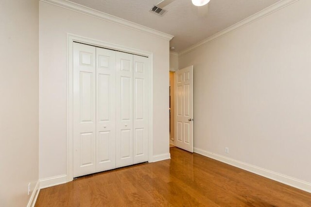 unfurnished bedroom with visible vents, baseboards, wood finished floors, and ornamental molding