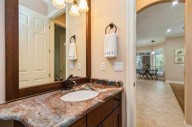 bathroom with tile patterned flooring, baseboards, ornamental molding, an inviting chandelier, and vanity