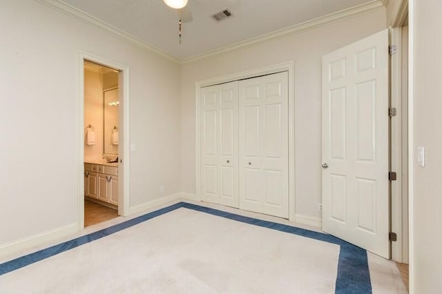 unfurnished bedroom with a closet, baseboards, light colored carpet, and crown molding