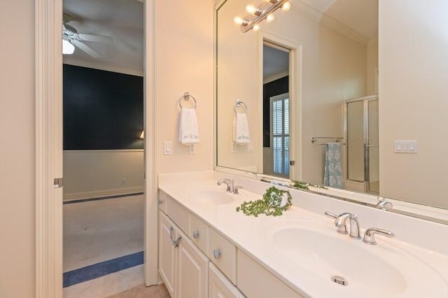 full bathroom with double vanity, a shower with shower door, ornamental molding, and a sink