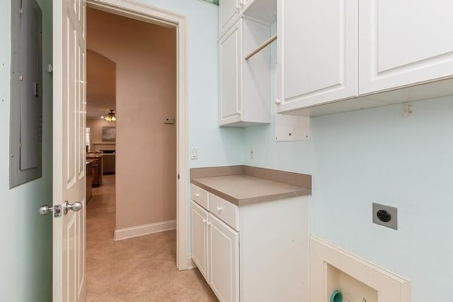 washroom with light tile patterned flooring, cabinet space, electric dryer hookup, and baseboards