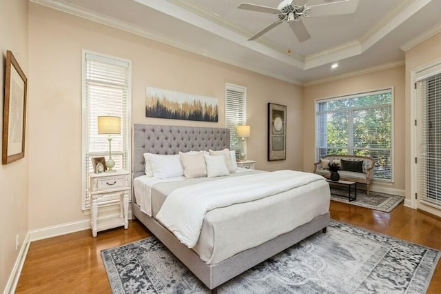 bedroom with wood finished floors, a raised ceiling, access to exterior, and ornamental molding