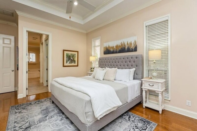 bedroom with ornamental molding, multiple windows, a raised ceiling, and wood finished floors