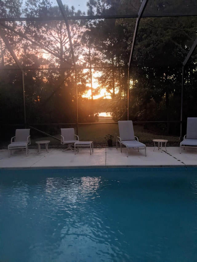 outdoor pool with a patio area and glass enclosure