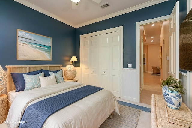 bedroom featuring visible vents, a closet, wainscoting, crown molding, and carpet flooring