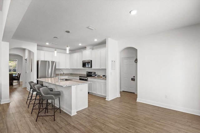 kitchen with a kitchen island with sink, sink, hardwood / wood-style floors, and appliances with stainless steel finishes