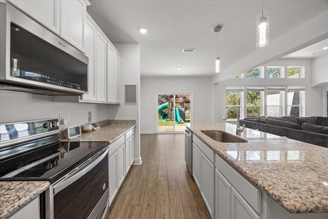 kitchen featuring appliances with stainless steel finishes, dark hardwood / wood-style flooring, a textured ceiling, sink, and white cabinetry