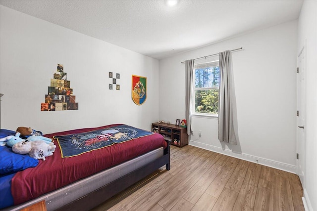 bedroom with a textured ceiling and light hardwood / wood-style flooring