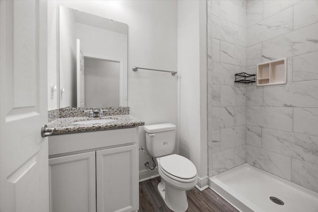 bathroom with vanity, toilet, wood-type flooring, and tiled shower