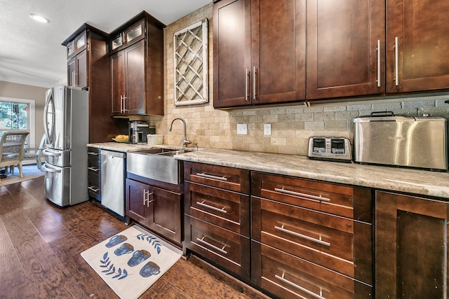 kitchen featuring light stone countertops, appliances with stainless steel finishes, dark brown cabinetry, and dark hardwood / wood-style floors