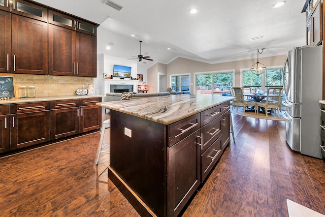 kitchen featuring stainless steel refrigerator, tasteful backsplash, dark hardwood / wood-style floors, vaulted ceiling, and a kitchen island