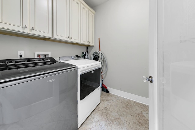 clothes washing area featuring washer and dryer and cabinets