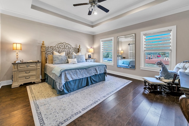 bedroom featuring a raised ceiling, crown molding, ceiling fan, and dark wood-type flooring