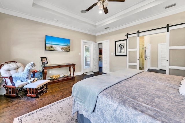 bedroom with a raised ceiling, ceiling fan, a barn door, and dark hardwood / wood-style flooring