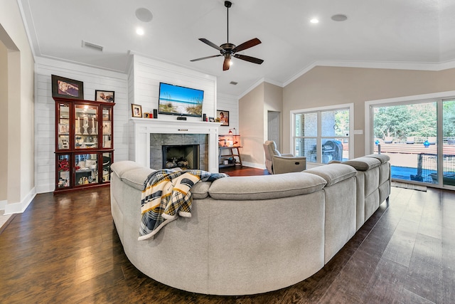 living room with ornamental molding, ceiling fan, dark hardwood / wood-style floors, lofted ceiling, and a tiled fireplace