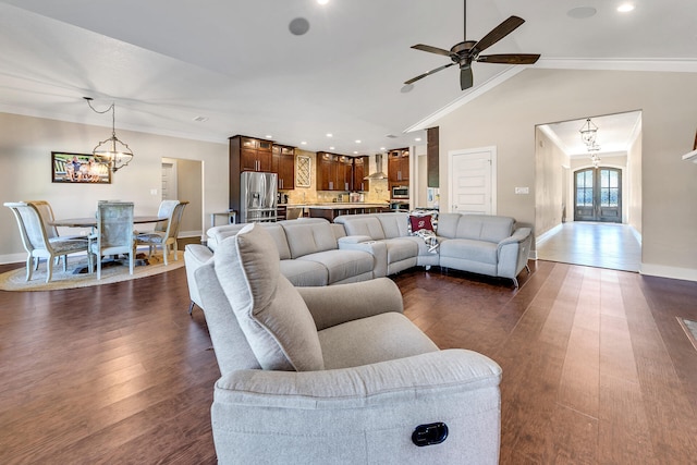 living room with ceiling fan with notable chandelier, dark hardwood / wood-style flooring, vaulted ceiling, and crown molding