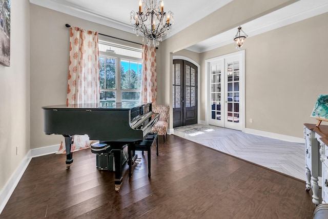 foyer entrance with crown molding, dark hardwood / wood-style flooring, a chandelier, and french doors