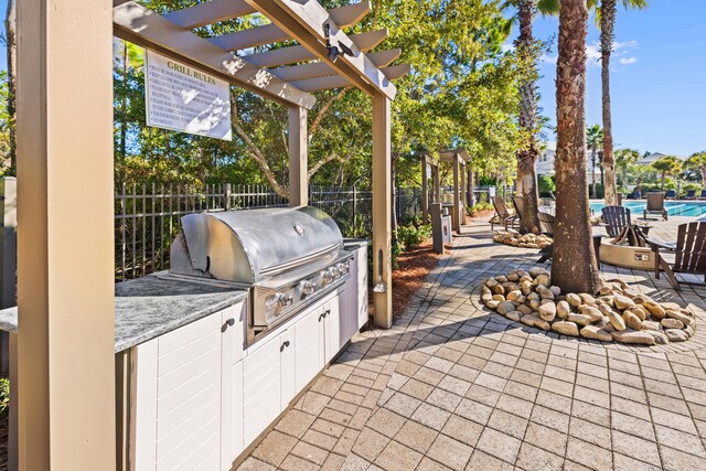 view of patio featuring grilling area, a pergola, a swimming pool, and exterior kitchen