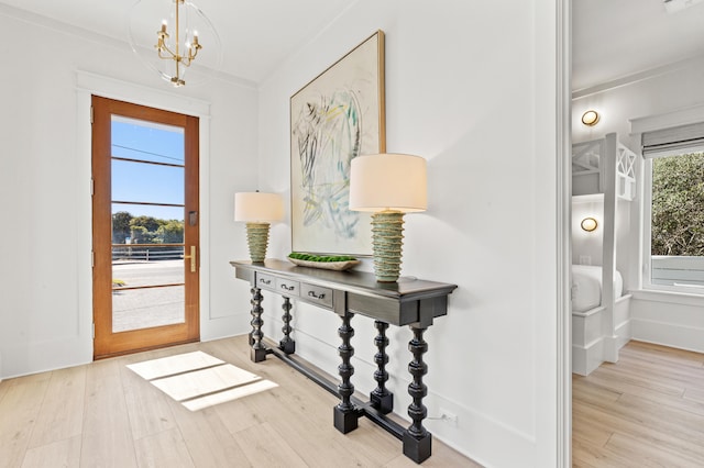 entrance foyer featuring ornamental molding, light hardwood / wood-style floors, and a notable chandelier