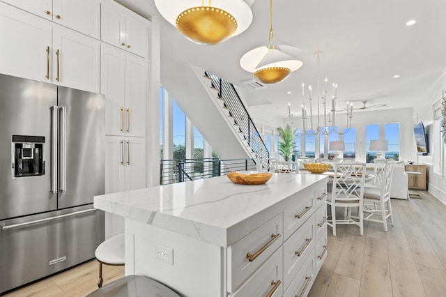 kitchen with light hardwood / wood-style flooring, a kitchen island, hanging light fixtures, and high end refrigerator