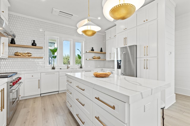 kitchen featuring light hardwood / wood-style floors, light stone counters, white cabinetry, and appliances with stainless steel finishes