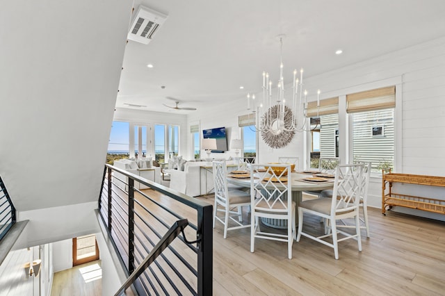 dining space featuring ceiling fan with notable chandelier and light hardwood / wood-style flooring