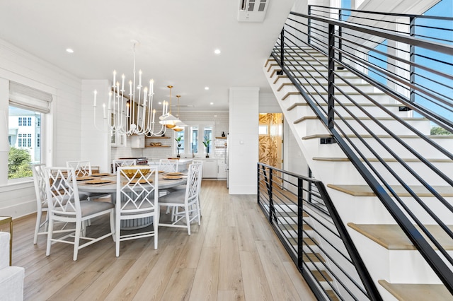 dining area with light hardwood / wood-style floors, ornamental molding, and a chandelier