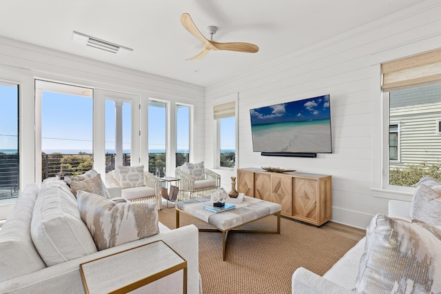 living room with hardwood / wood-style flooring, ceiling fan, and wooden walls