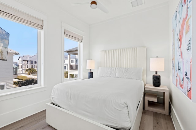 bedroom featuring ceiling fan, wood-type flooring, and crown molding