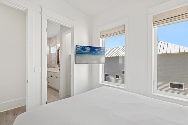 bedroom featuring ensuite bath, crown molding, and light hardwood / wood-style floors