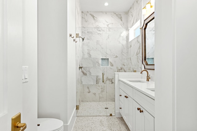 bathroom featuring a shower with door, vanity, and toilet