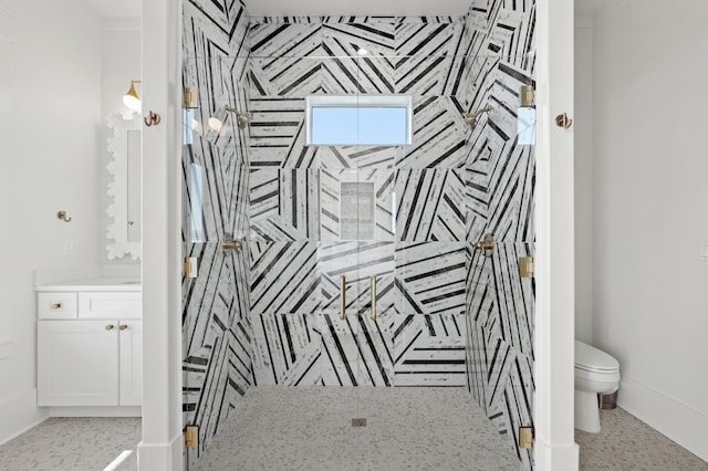 bathroom featuring a tile shower, vanity, and toilet