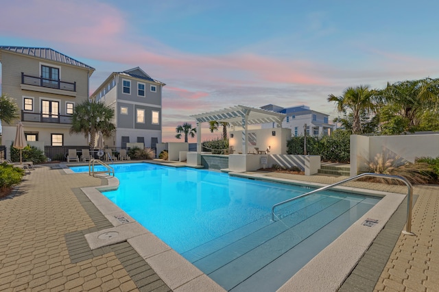 pool at dusk featuring a pergola and a patio area