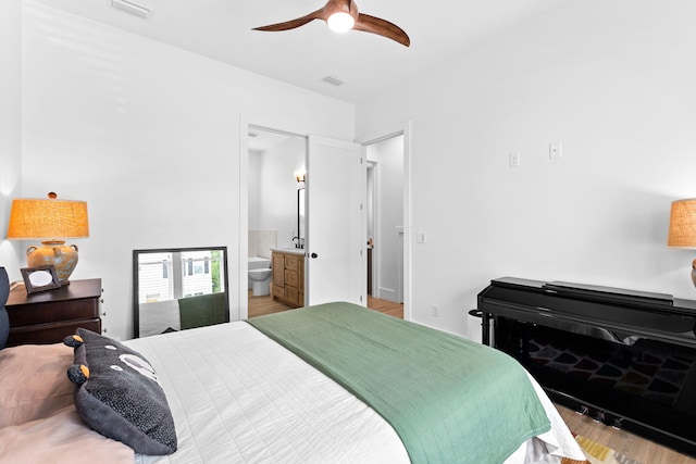 bedroom with connected bathroom, light hardwood / wood-style flooring, and ceiling fan