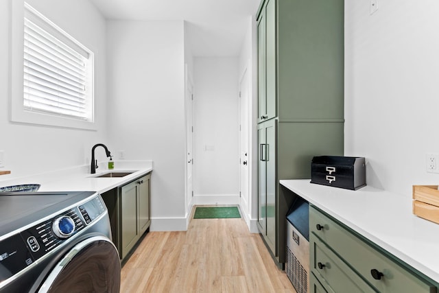 washroom featuring light hardwood / wood-style floors, sink, cabinets, and washer / dryer