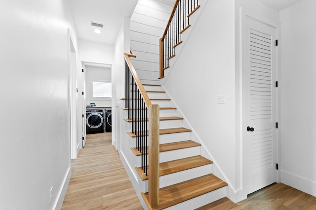 staircase with hardwood / wood-style floors and washer and dryer