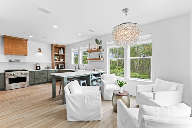 kitchen featuring an inviting chandelier, sink, hanging light fixtures, stainless steel stove, and light wood-type flooring