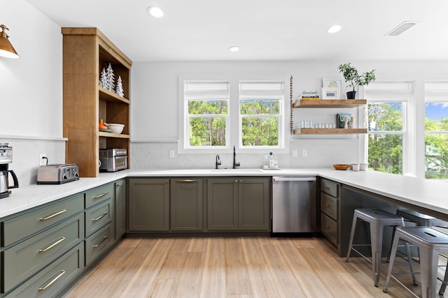 kitchen featuring tasteful backsplash, a wealth of natural light, stainless steel dishwasher, and light wood-type flooring