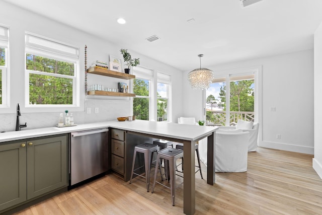 kitchen with dishwasher, sink, hanging light fixtures, light hardwood / wood-style flooring, and a notable chandelier