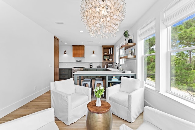 dining area featuring sink, light hardwood / wood-style flooring, and a notable chandelier