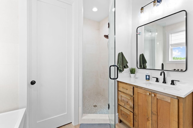 bathroom featuring a shower with door and vanity